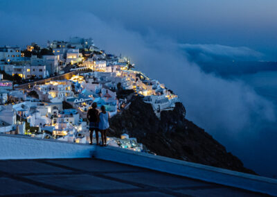 A couple looking over Fira and the Caldera, Santorini. Blue light in the evening. ISO 6400, Nikon D700.